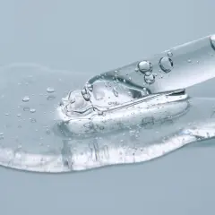 Kropla przejrzystego serum z bąbelkami powietrza spływa z pipety. To połączenie ceramidów a peptydów dla zdrowej skóry.