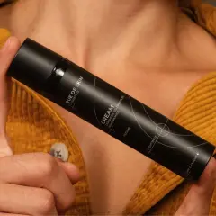 Dłoń trzyma czarny flakon kremu z napisem "Niacynamid". Czy wybrać retinol czy niacynamid?