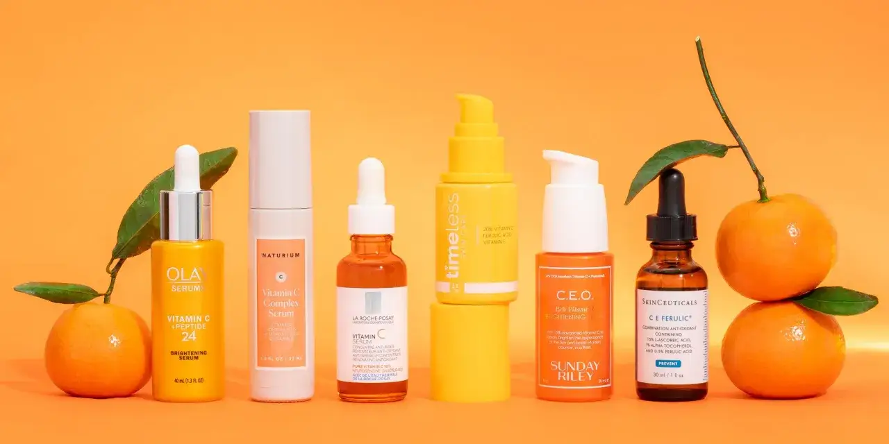 Siedem serum z witaminą C, w tym Olay, Naturium, La Roche-Posay, Timeless, Sunday Riley i SkinCeuticals, obok pomarańczy. Efekty witaminą C na twarz są obiecujące.